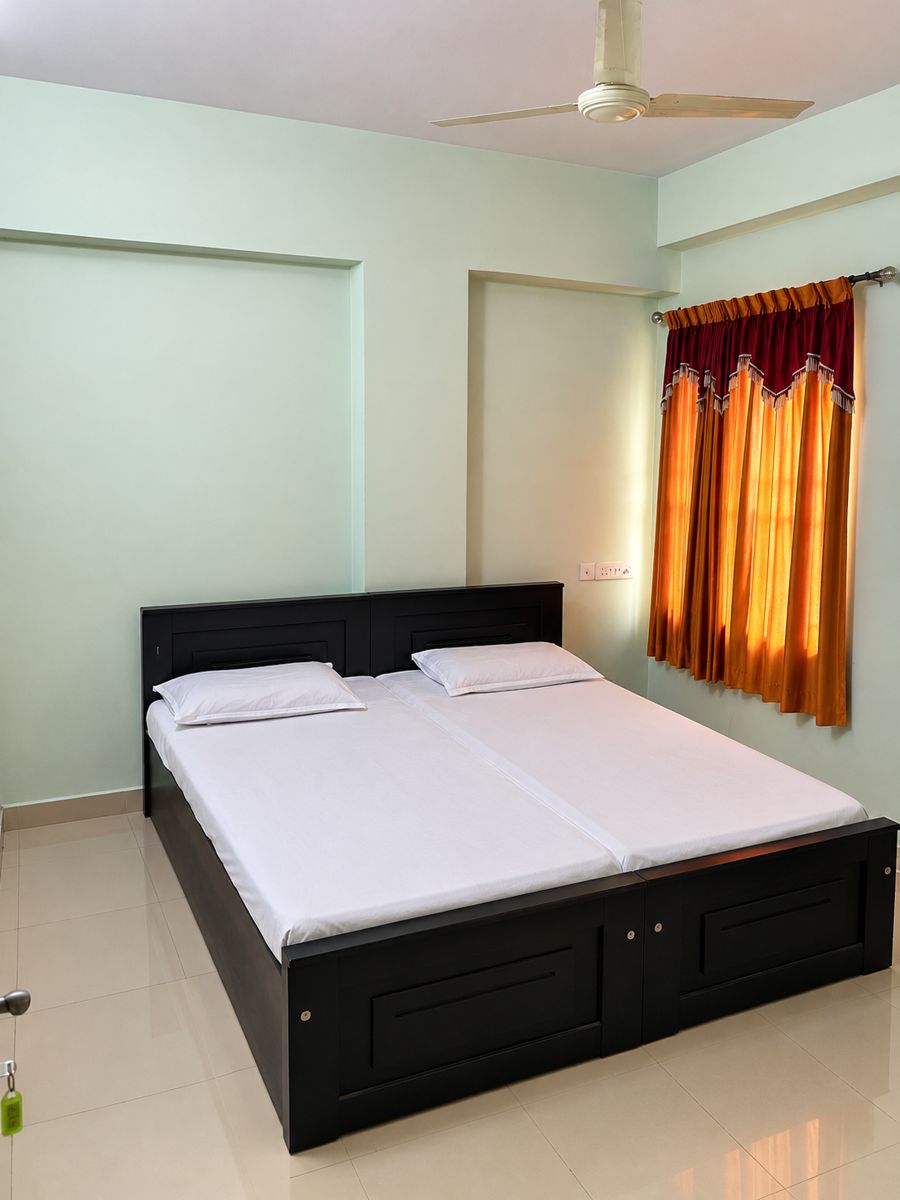 Bedroom with two single beds pushed together, white linen, mint walls and orange curtains